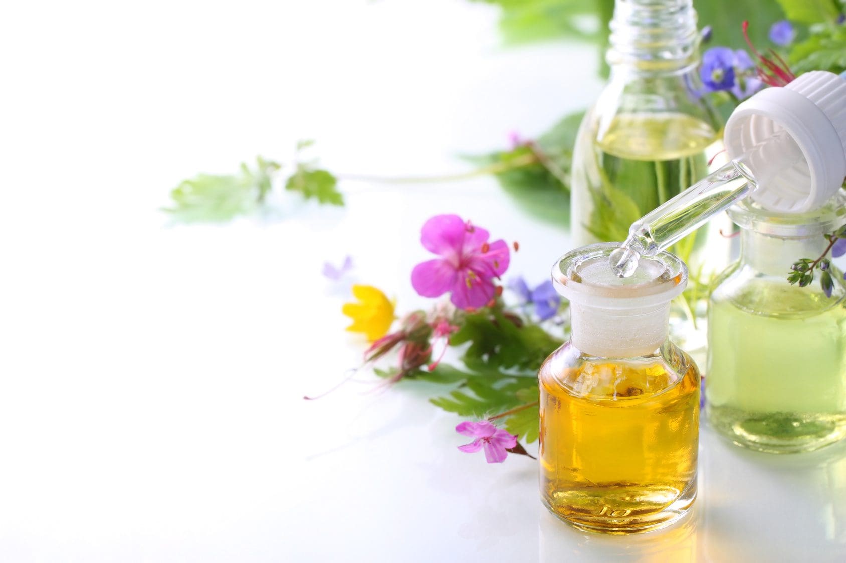Blüten und Blätter liegen hinter Glasgefäßen mit einer Pipette.